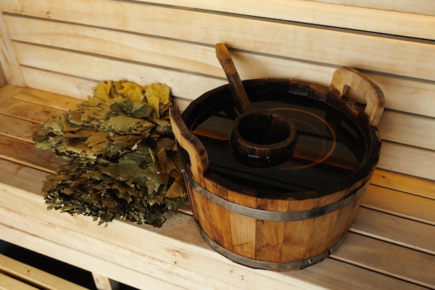 Concha de balde de madeira de sauna e vassoura de folhas em tábuas de madeira