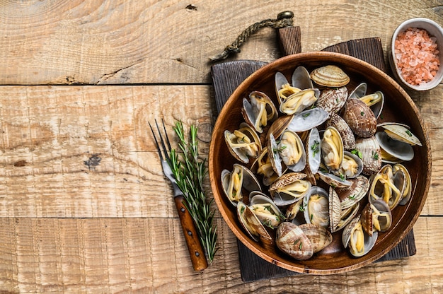 Conchas cozidas no vapor Moluscos vongole em um prato de madeira