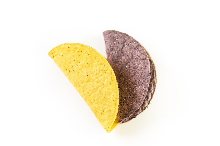 Foto conchas de taco de milho azuis e amarelas em um fundo branco.