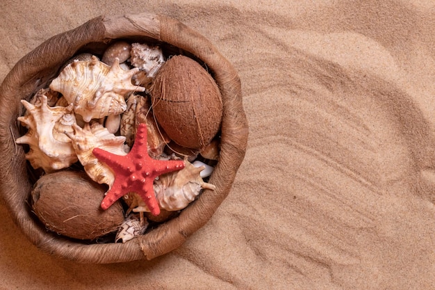 Foto conchas em uma cesta de vime na areia férias de verão no fundo do mar com espaço para texto vista de cima