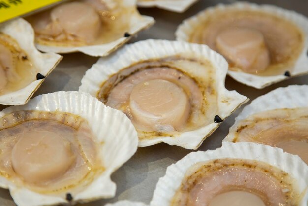 Foto conchas de mariscos y pescado cocinados en una parrilla en el mercado de pescado de osaka, japón