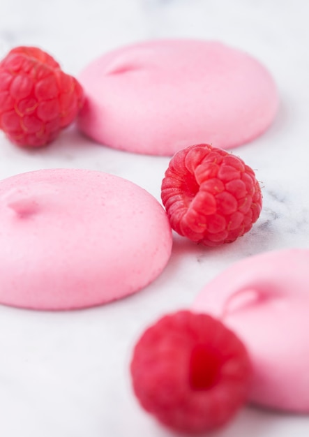 Conchas de merengue dulce rosa con frambuesas frescas