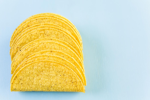 Foto conchas de taco de maíz amarillo sobre un fondo azul.