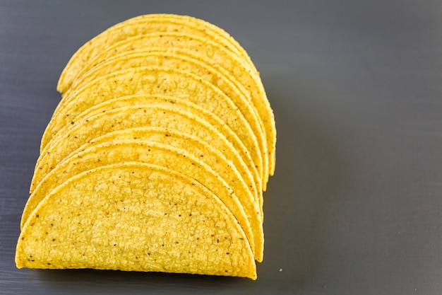 Foto conchas de taco de maíz amarillo sobre un fondo gris.