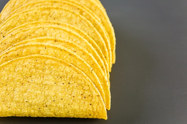 Conchas de taco de maíz amarillo sobre un fondo gris.