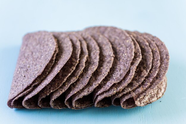 Conchas de taco de maíz azul sobre un fondo azul.