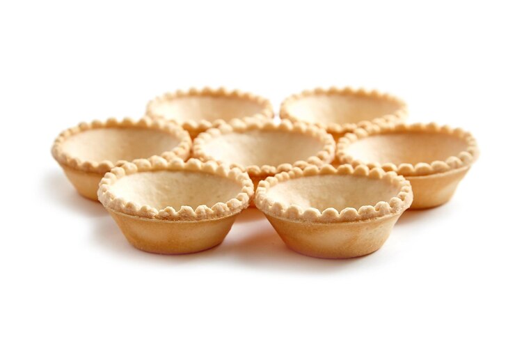 Conchas de tartaleta sin relleno aisladas sobre fondo blanco Siete conchas de mini tarta crujientes