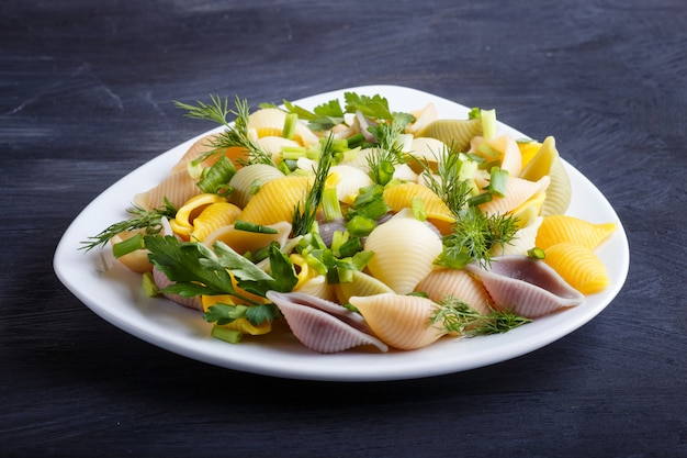 Conchiglie färbte Teigwaren mit frischem Gemüseladen auf schwarzem Holztisch