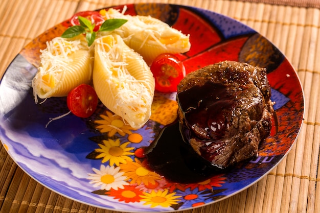 Foto conchiglioni al horno con requesón y filete de ternera servido en el plato