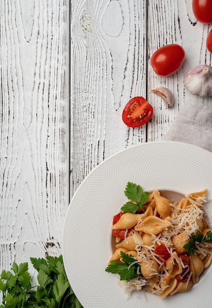 Conchiglioni-Nudeln mit Kirschtomaten-Käse und Petersilie in weißer Platte auf Holzuntergrund