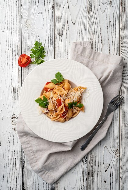 Conchiglioni-Nudeln mit Kirschtomaten-Käse und Petersilie in weißer Platte auf Holzuntergrund