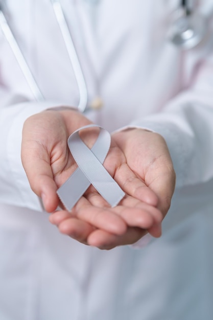 Concientización sobre el cáncer cerebral Mayo mes Médico con cinta de color gris para apoyar a las personas vivas Concepto de salud y día mundial del cáncer