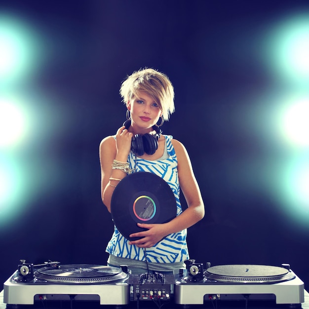 Concierto de retrato y DJ de mujer con mezclador en fondo oscuro para entretenimiento en discotecas o fiestas de música danza o actuación con luz para la actuación y disc jockey mezclando audio o sonido