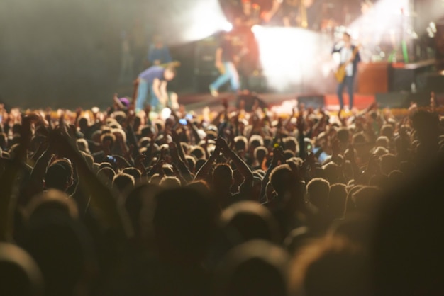 Foto concierto en vivo de la multitud y escenario con público bailando como festival de música para espectáculos de entretenimiento o carnaval manos de la gente y fans de músicos con iluminación para evento de rock rave o vacaciones