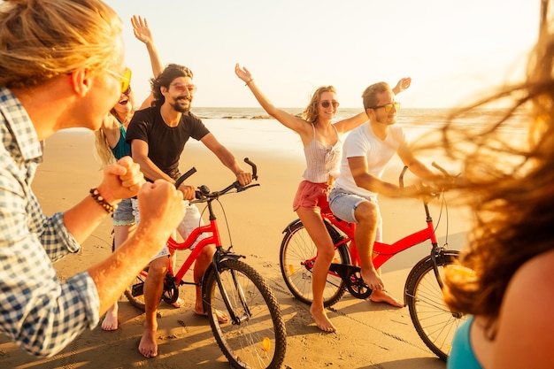 Concurso de amigos felices en bicicleta y hombre deportivo dando a su novia paseos a cuestas vacaciones de libertad de verano en el mar