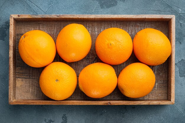 Condado de Florida naranja, frutas saludables, en caja de madera, sobre mesa de piedra gris, vista superior laicos plana