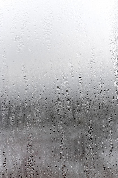 Condensação de fundo natural vertical em vidro com gotas fluindo para baixo de umidade e neblina em branco Fora chuva de mau tempo