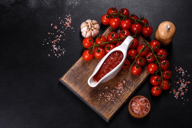 Condimento picante de la cocina georgiana adjika en un bol con tomates rojos en un primer plano de una mesa de hormigón