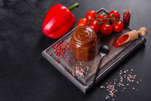 Condimento picante de la cocina georgiana adjika en un recipiente con pimiento rojo y ajo en una mesa de hormigón de cerca