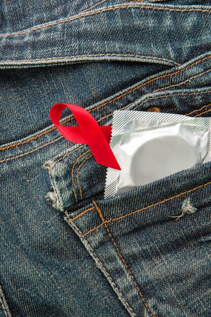 Condom no bolso jeans com fita de consciência vermelha