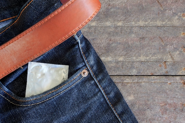 condón en el bolsillo trasero de los pantalones vaqueros con el fondo de la tabla de madera