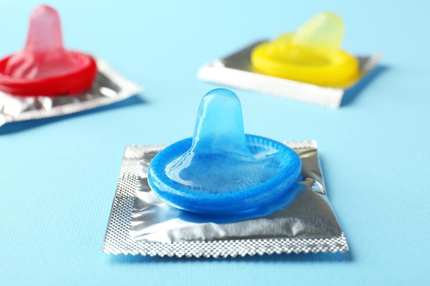 Condones abiertos y envueltos sobre fondo de color Concepto de sexo seguro