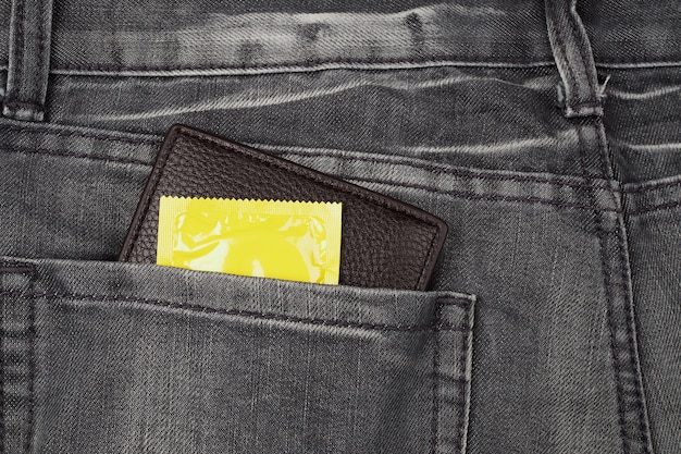 Condones y billetera en el bolsillo de jeans gris.