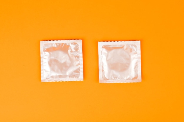 Condones sobre un fondo naranja El concepto de prevención y sexo seguro