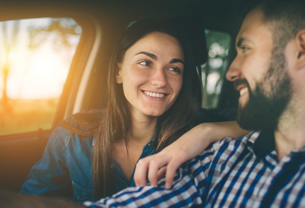 Condução cuidadosa. Lindo casal jovem sentado nos assentos do passageiro da frente e sorrindo enquanto homem bonito, dirigindo um carro.