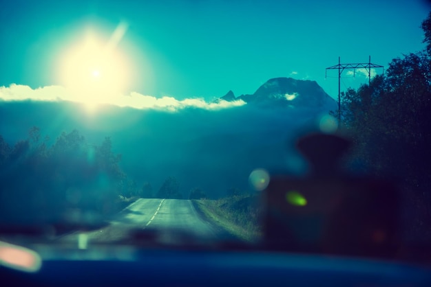 Conducir un automóvil en una carretera de montaña Cielo con sol atardecer Naturaleza Noruega Círculo polar Vista a través del parabrisas