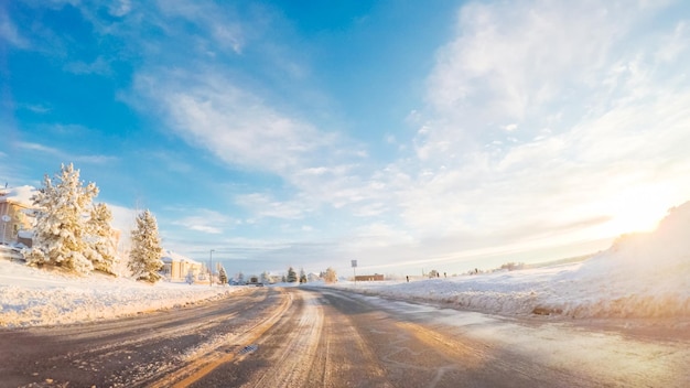 Conducir por la carretera suburbana después de la tormenta de nieve de primavera.