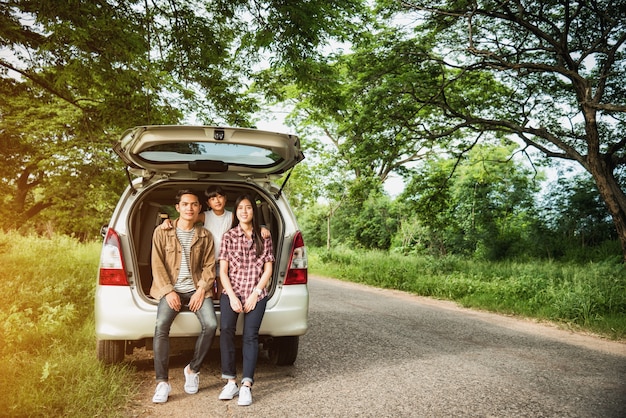 conducir en la familia de vacaciones; familia asiática está feliz sentado en el maletero abierto de un coche