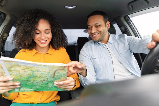 Conductor árabe apuntando al mapa en manos de mujeres en auto