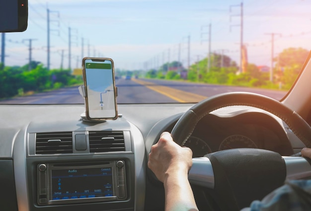 Conductor de automóvil que usa un teléfono inteligente con una aplicación de navegación de mapas GPS mientras conduce por la carretera