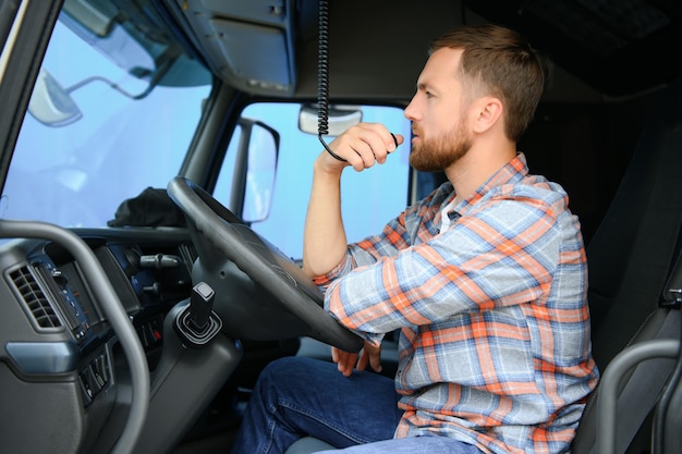 Conductor de camión masculino hablando por sistema de radio CB en su vehículo