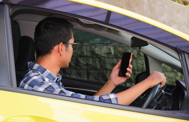 Foto un conductor de coche mirando a la pantalla en blanco del teléfono móvil que sostiene