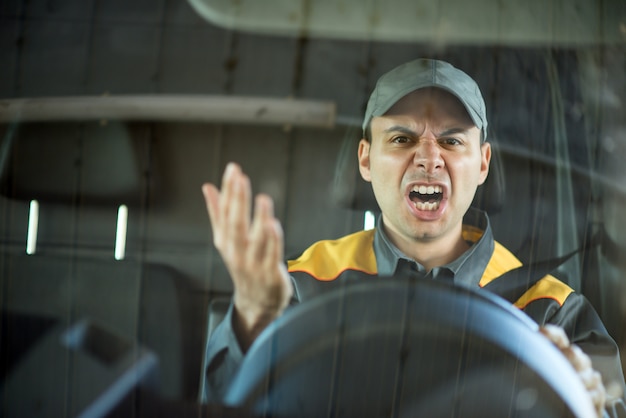 Conductor enojado gritando en su vehículo.