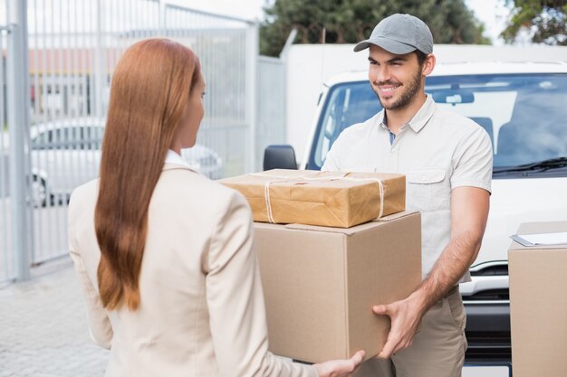 Conductor de entrega pasando paquetes al cliente feliz