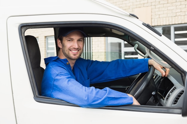 Conductor de entrega sonriendo a la cámara en su camioneta