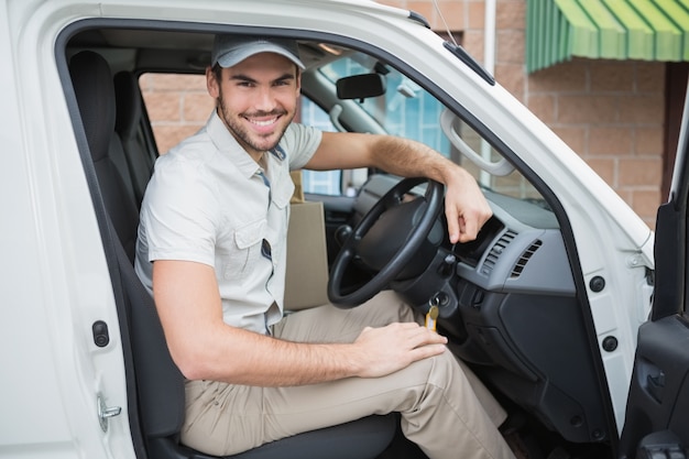 Conductor de entrega sonriendo a la cámara en su camioneta