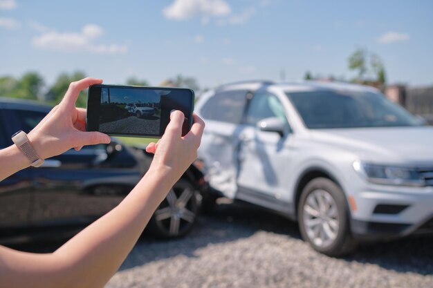 Conductor estresado tomando una foto en la cámara del teléfono de un vehículo destrozado que pide ayuda al servicio de emergencia después de un accidente automovilístico Concepto de seguridad y seguro vial