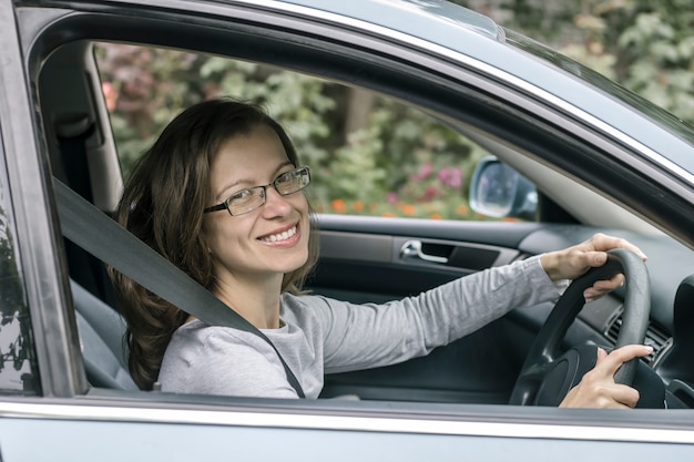 Foto el conductor feliz de la mujer joven se sienta en coche.