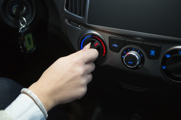 Foto conductor femenino girando la perilla del aire acondicionado del coche