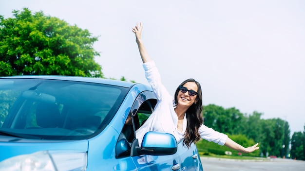 Conductor femenino moderno feliz hermoso en gafas de sol conduciendo un coche. Nuevo concepto de coche. Visita en concesionario