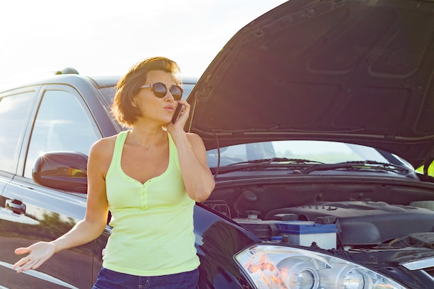 Conductor frustrado de la mujer cerca del coche roto.