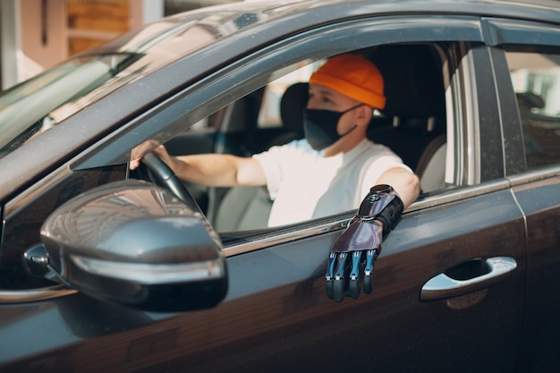 Conductor joven discapacitado con mano protésica artificial conduciendo el coche del vehículo