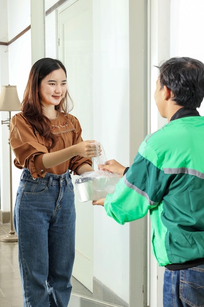 Foto conductor en línea entregando café y comida a una cliente femenina