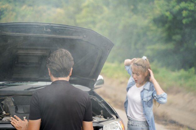 Un conductor masculino comprueba el estado de un coche tras un accidente con un motor que echa humo