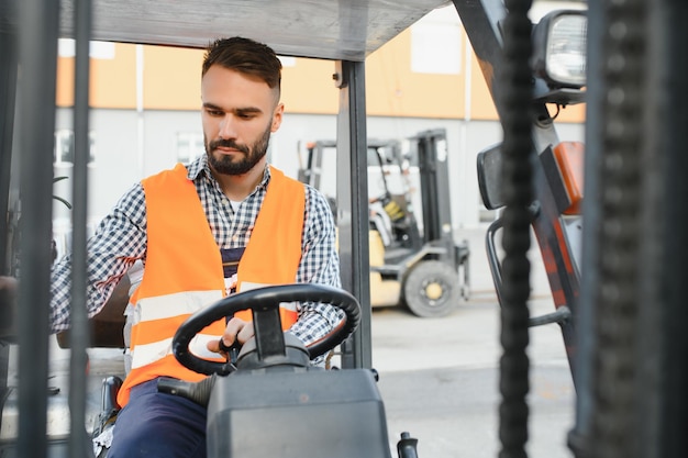 Conductor de montacargas ondeando en el almacén de una empresa de transporte mientras conduce el montacargas