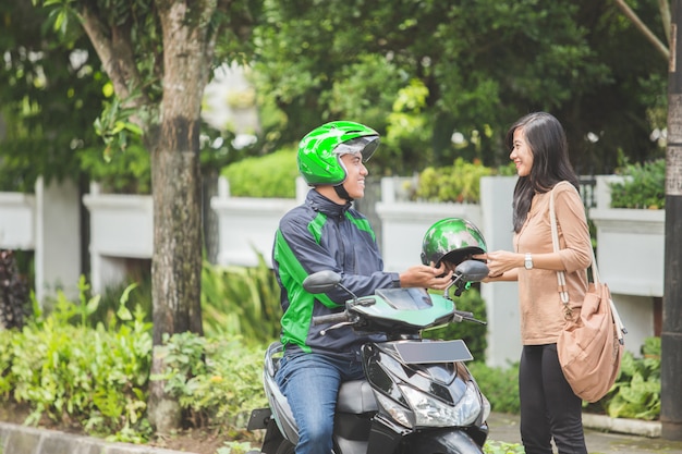 Conductor de moto comercial dando casco a su cliente